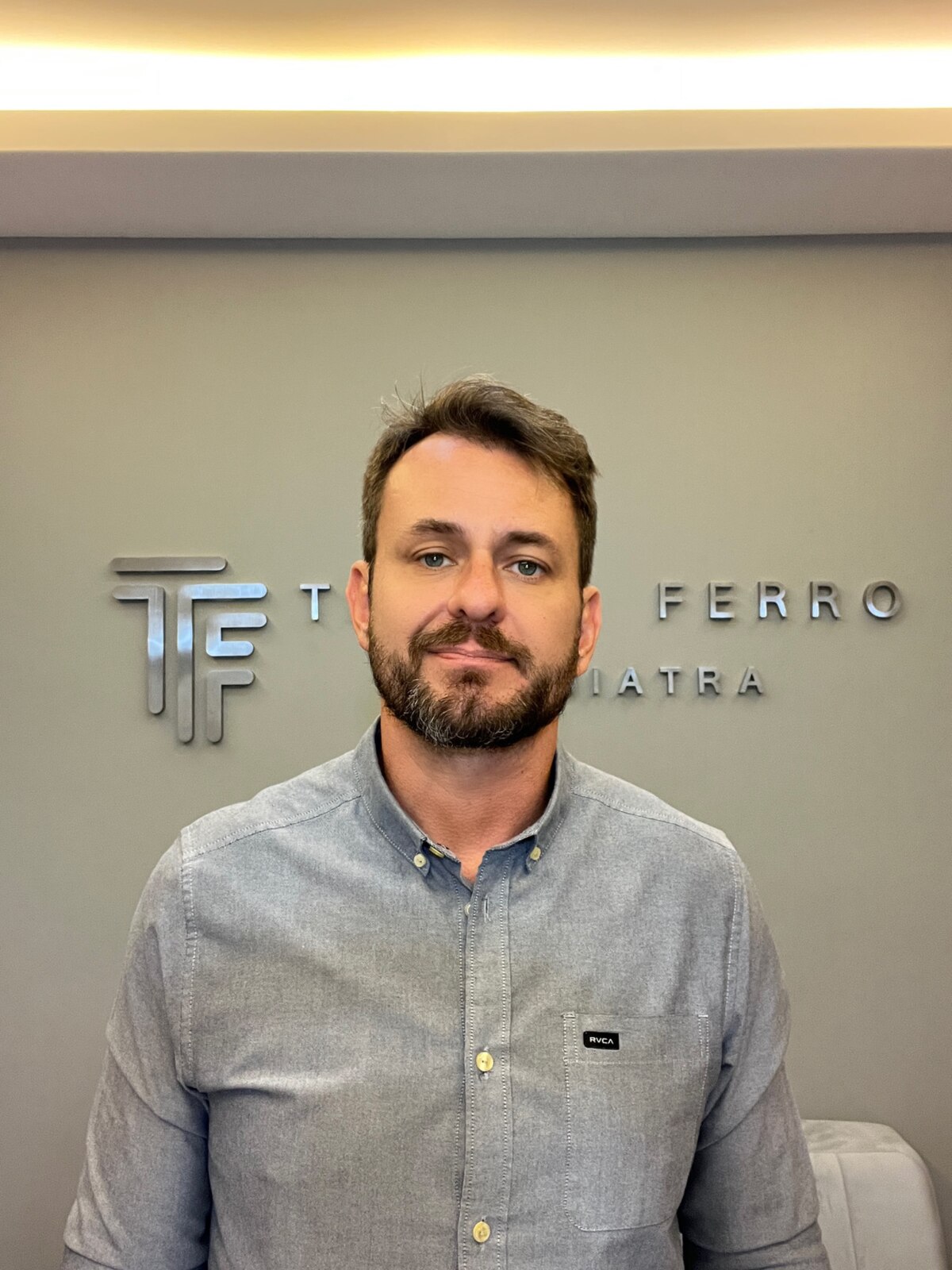 Dr. Thiago Ferro diante da identidade visual do consultório